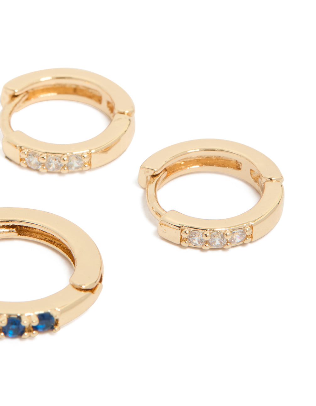 Designed with gold cubic zirconia huggie earrings featuring clear and sapphire stones in a 3-pack close up view