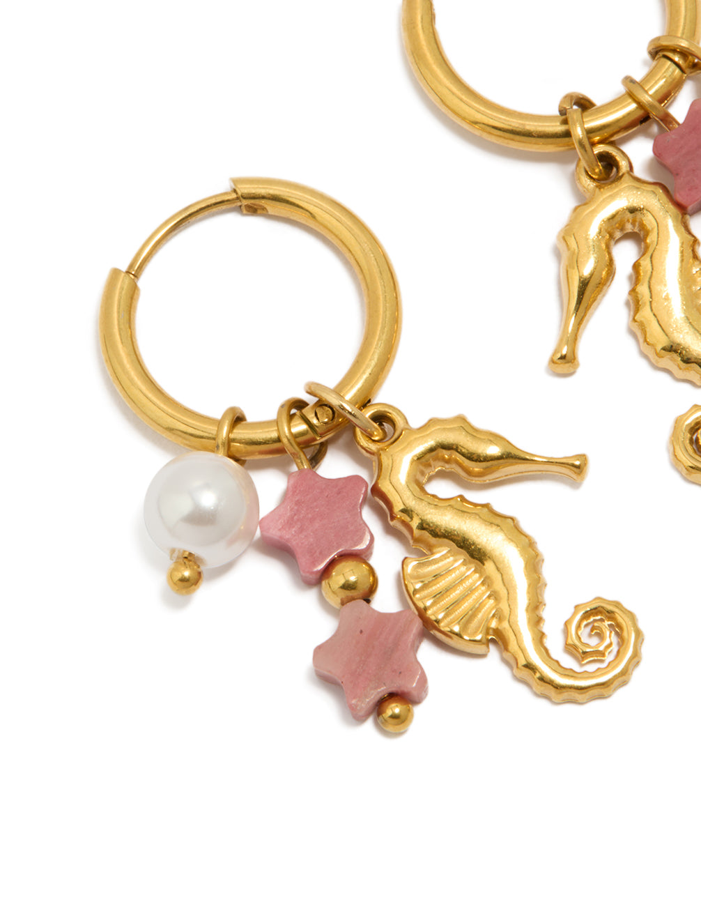 Showcasing waterproof gold plated stainless steel seahorse pearl charm huggie earrings with ocean details in pink and white close up view