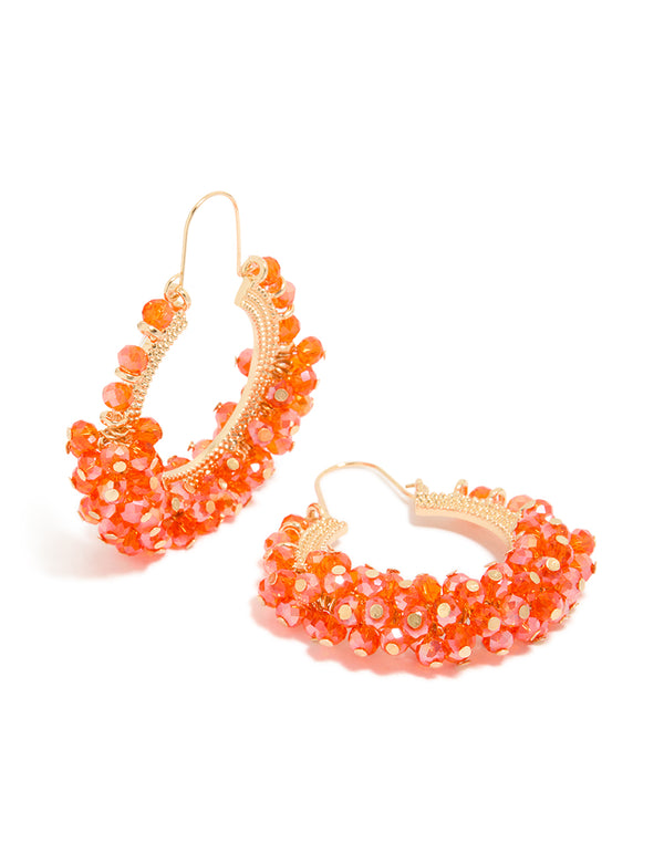 Featuring statement hoop earrings with beads crafted from coral and gold accessories front view
