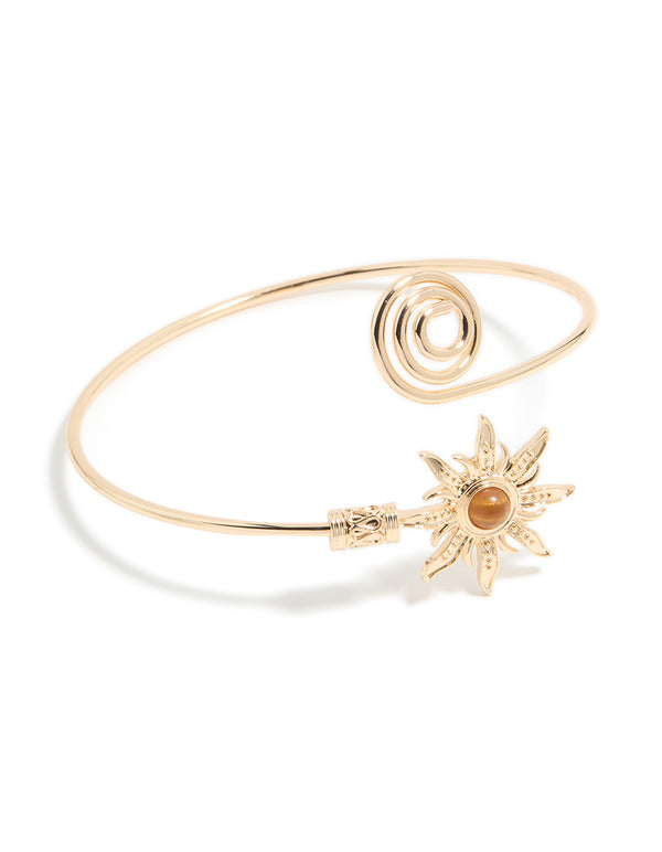 Featuring celestial sun detailing and a swirl design, this gold statement cuff is shown in front view