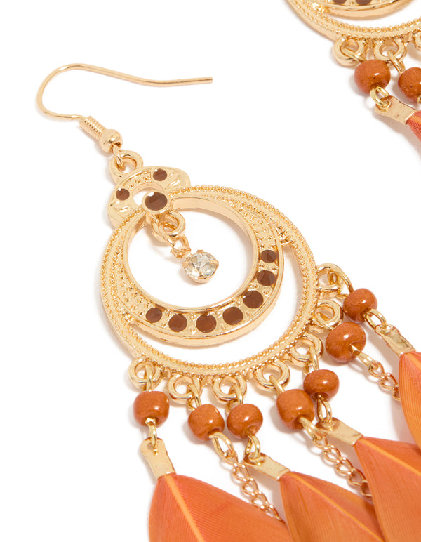 Highlighting statement drop earrings featuring beads, and coral feathers with gold detailing close up view