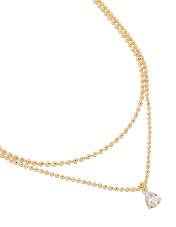 Showcasing a gold plated cubic zirconia teardrop pendant and ball layered necklace featuring crystal in dainty style close up view