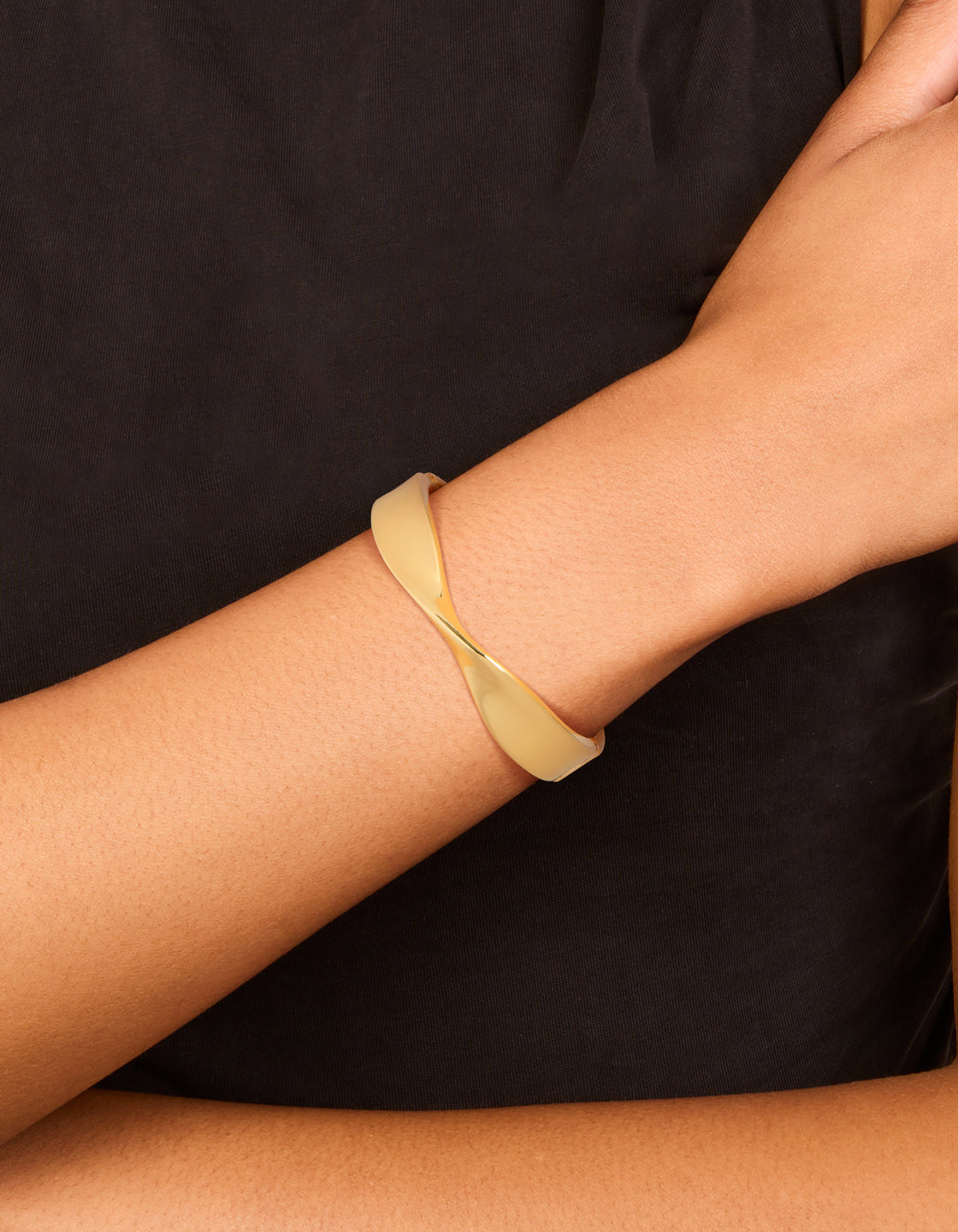 Crafted from gold plated material, this twisted thick bangle in gold with chunky style on wrist view