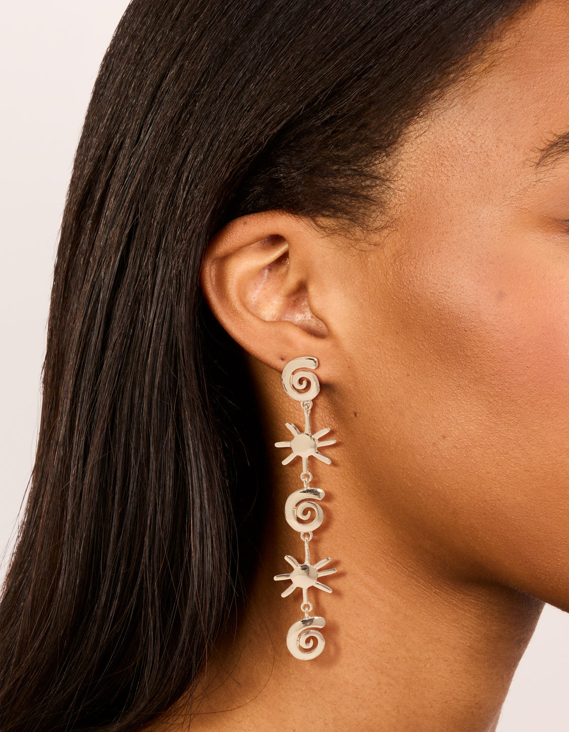 Showcasing gold shell and sun drop earrings with statement celestial charm design on ear view