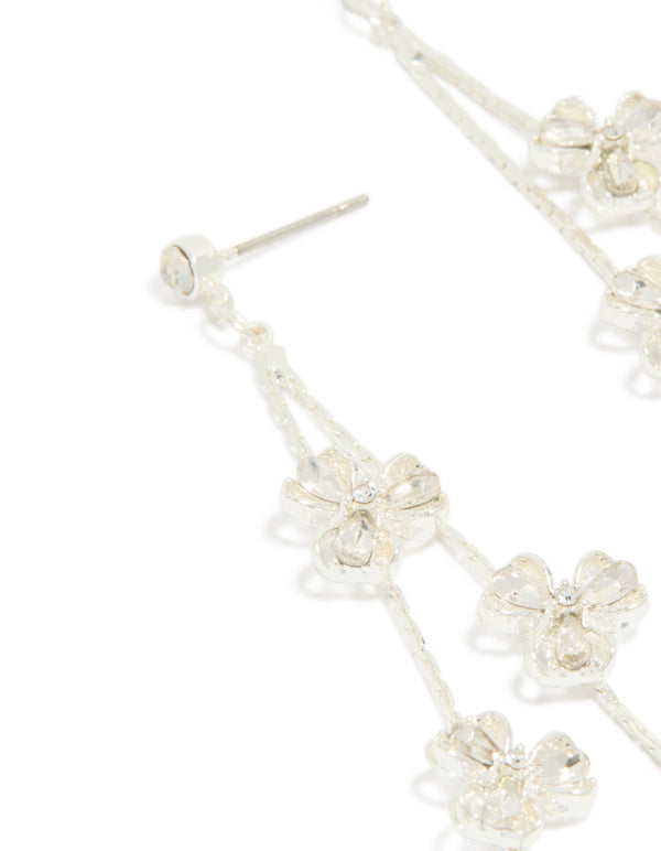 Highlighting dainty silver floral drop earrings with intricate petal detailing and clear finish close up view