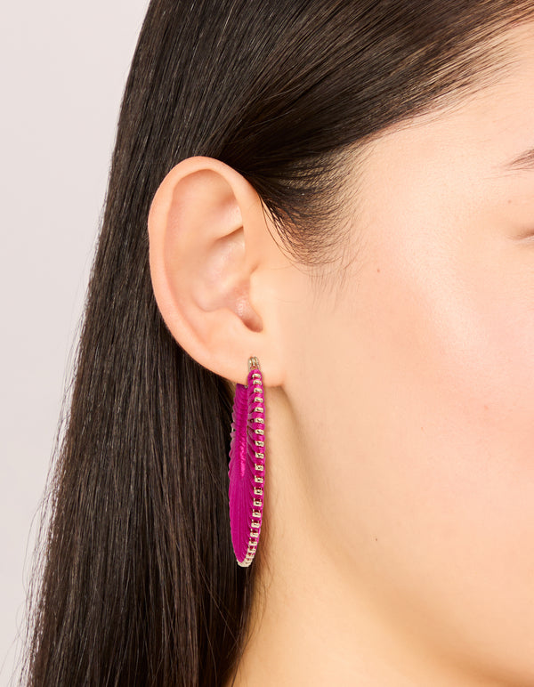 Showcasing hot pink threaded hoop earrings with statement style and gold detailing on ear view