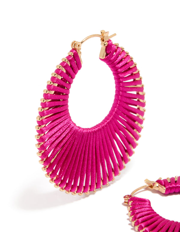 Detailed view of hot pink threaded hoop earrings in statement style with gold accents close up view
