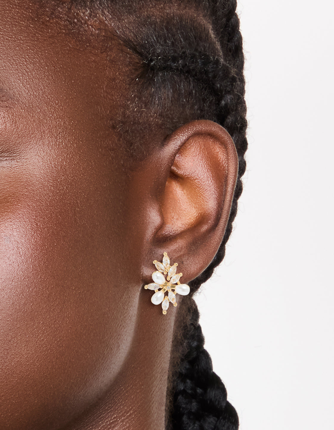Showcasing gold plated cubic zirconia organic flower and pearl earrings with statement style on ear view