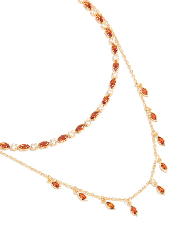 Showcasing a gold plated red cubic zirconia tennis and teardrop charm layer necklace with statement styling close up view