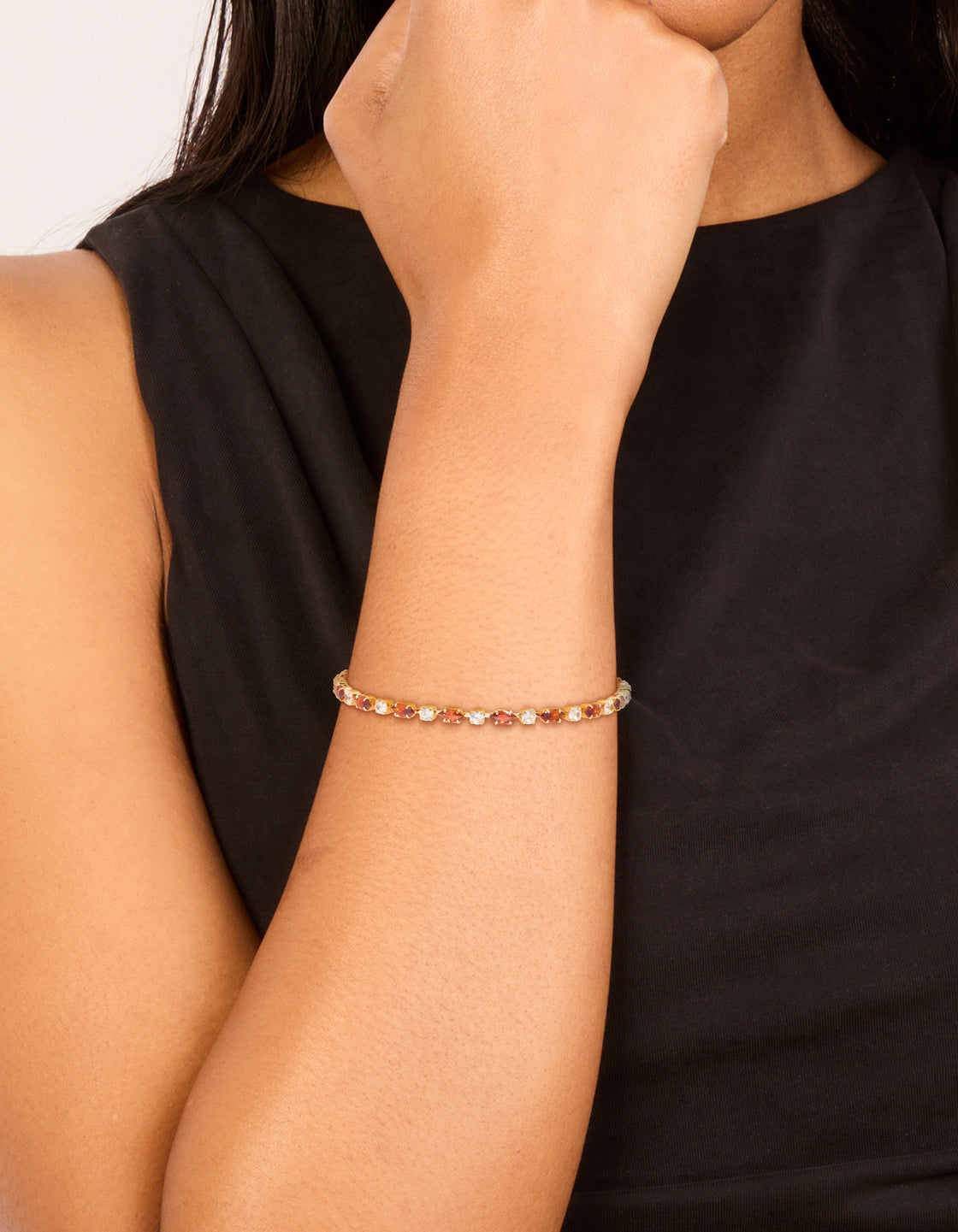 Featuring a gold plated clear and cognac cubic zirconia multi cut tennis bracelet on wrist view