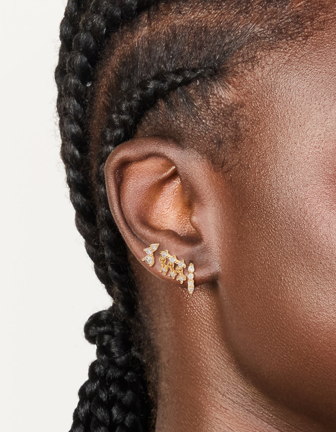Featuring dainty gold plated cubic zirconia trio studs and huggie earrings in a 3-pack on ear view