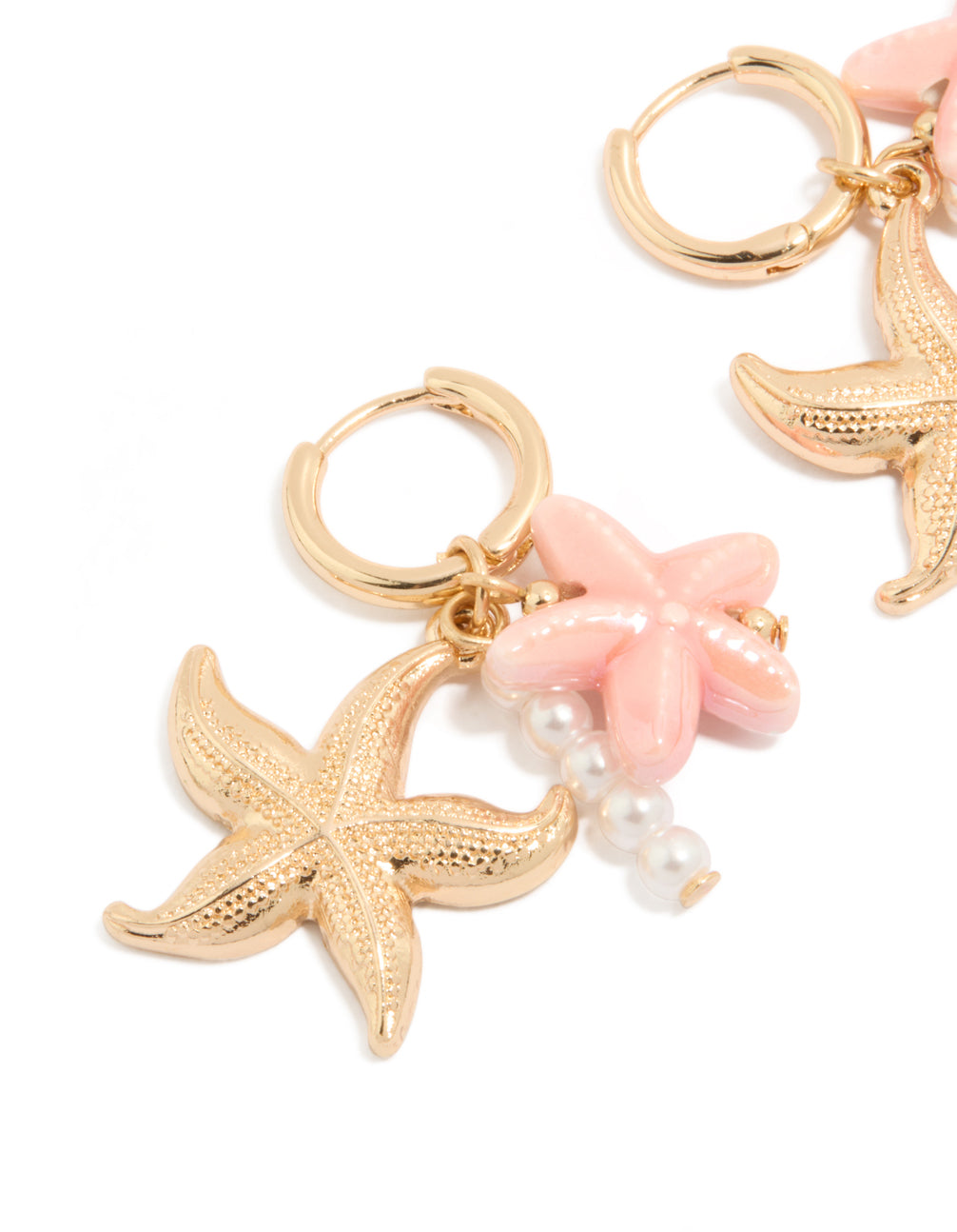 Showcasing dainty gold huggie earrings featuring pearl, pink flower, and starfish ocean theme charm drops in light pink and white close up view