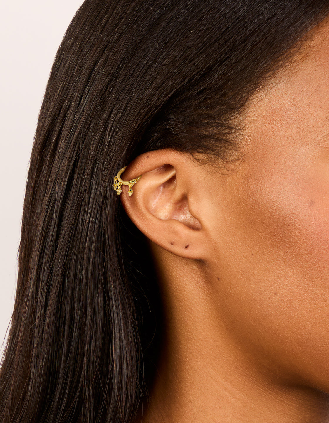 Crafted from gold plated surgical steel with cubic zirconia celestial star charm clicker ring in dainty style on ear view