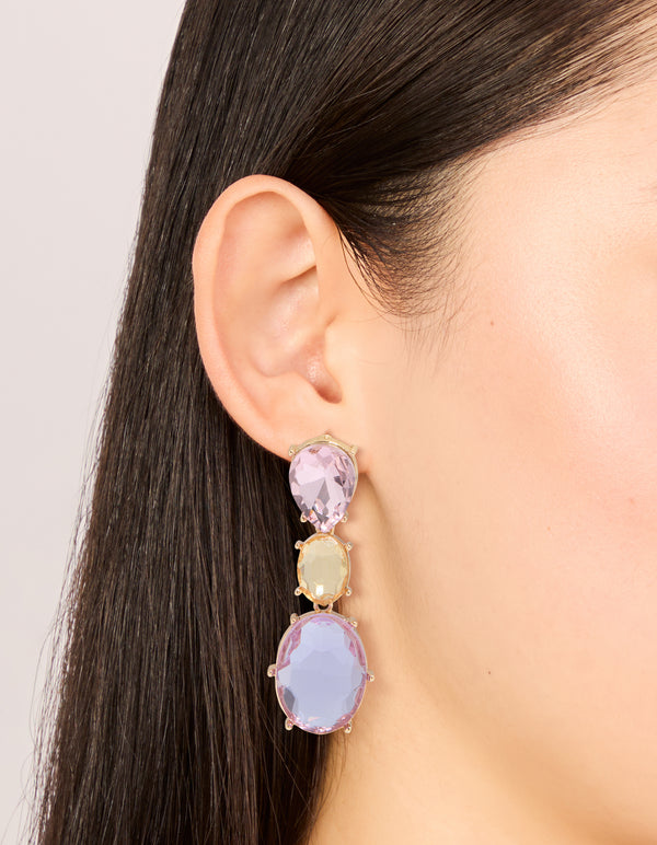Featuring statement drop earrings with oval cut stones in purple and orange hues set in gold on ear view