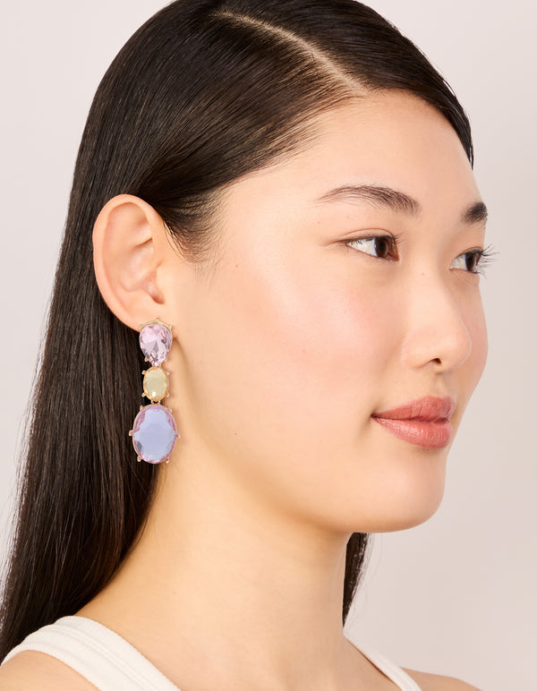 Crafted with statement drop earrings featuring oval cut stones in purple and orange hues set in gold on model view