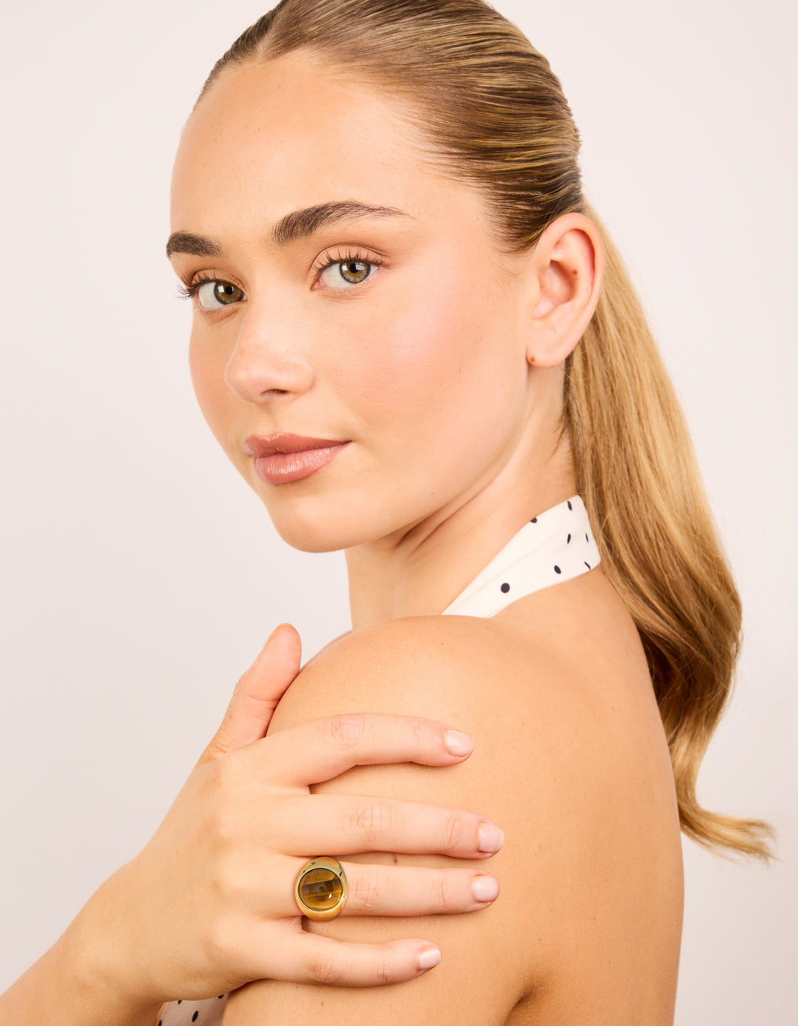 Featuring a gold plated statement ring with large brown stone on finger view
