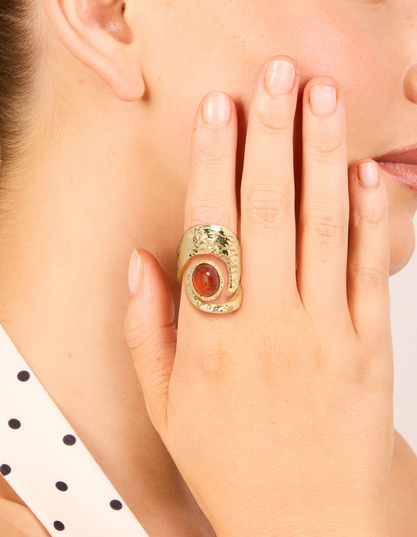Showcasing a statement gold plated molten large stone ring with dark orange cabochon on finger view