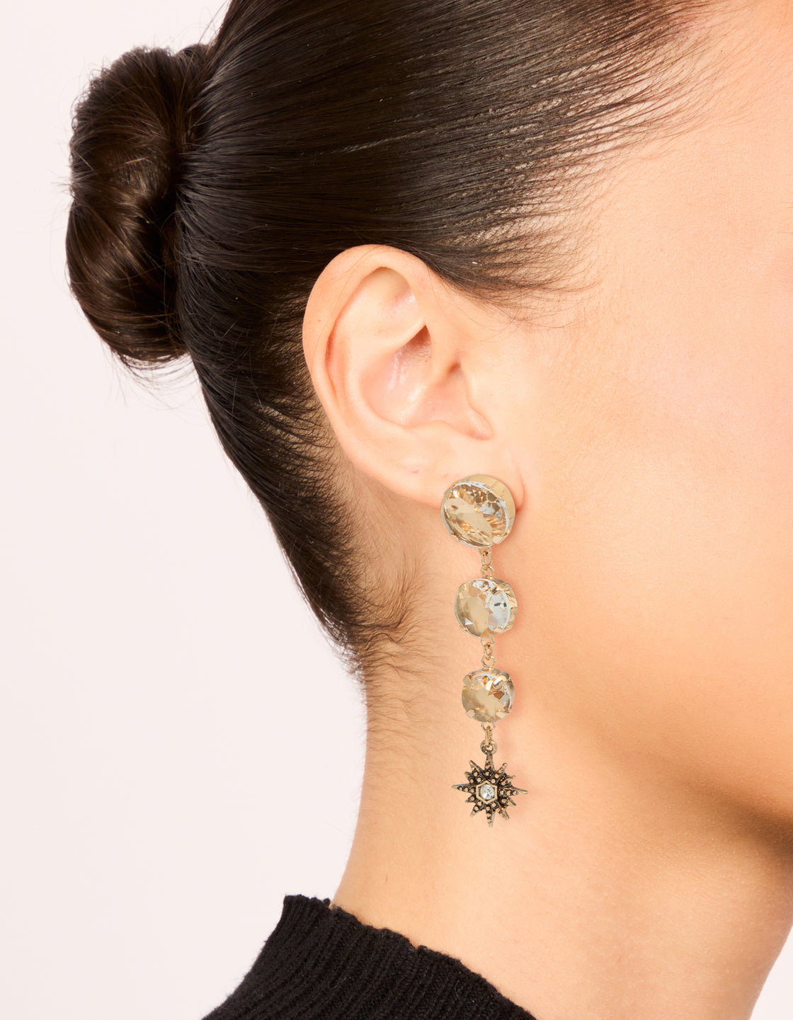 Elegant gold triple jewel drop earrings with celestial star charms on ear view