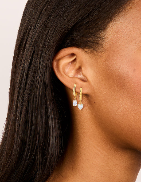 Featuring waterproof huggie drop earrings in a 2-pack, crafted from gold plated stainless steel heart features, cubic zirconia accents in clear on ear view