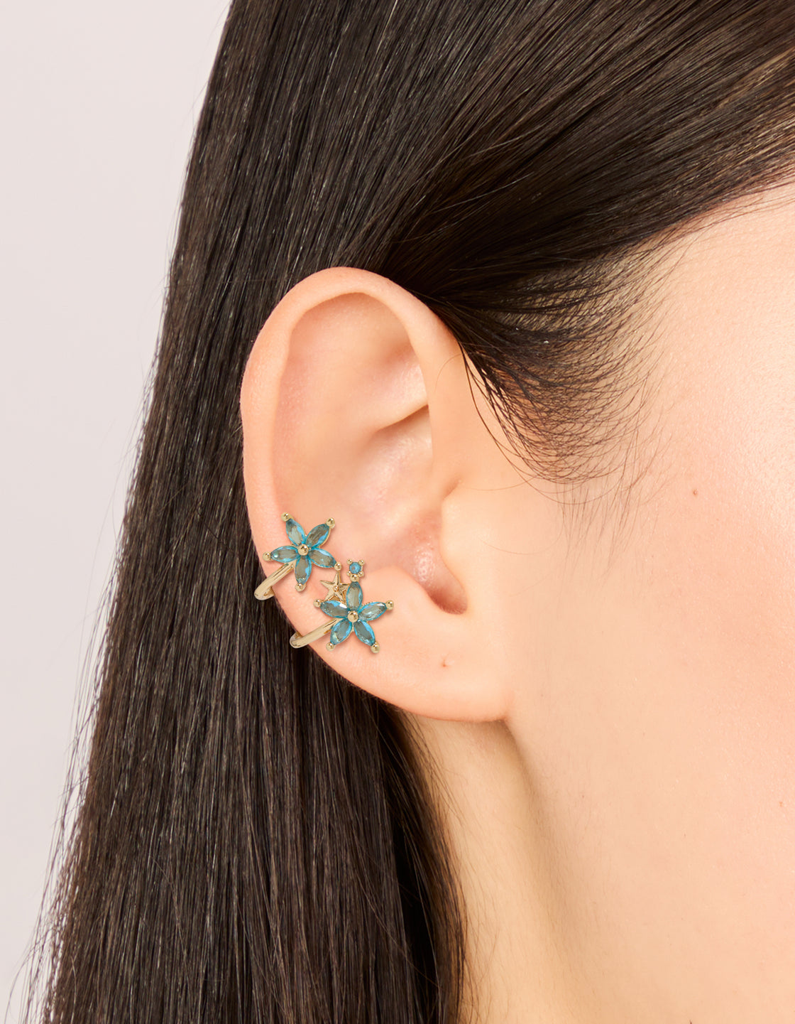 Elegant gold blue cubic zirconia flowers ear cuff with floral design and huggie closure on ear view