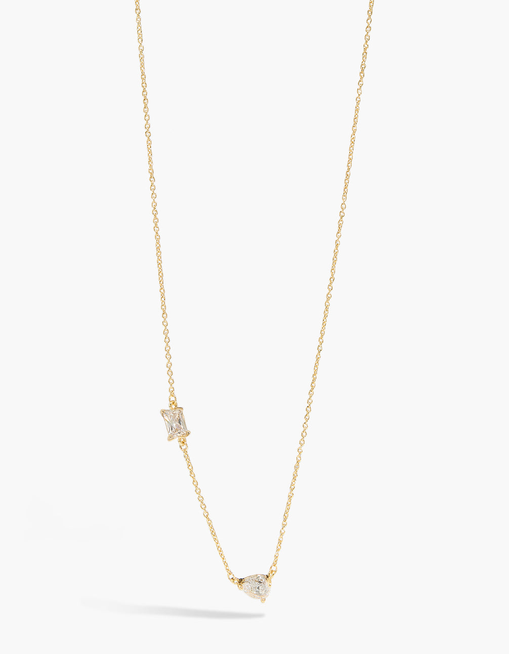 Showcasing a gold plated teardrop and square cubic zirconia station necklace with crystal accents close up view