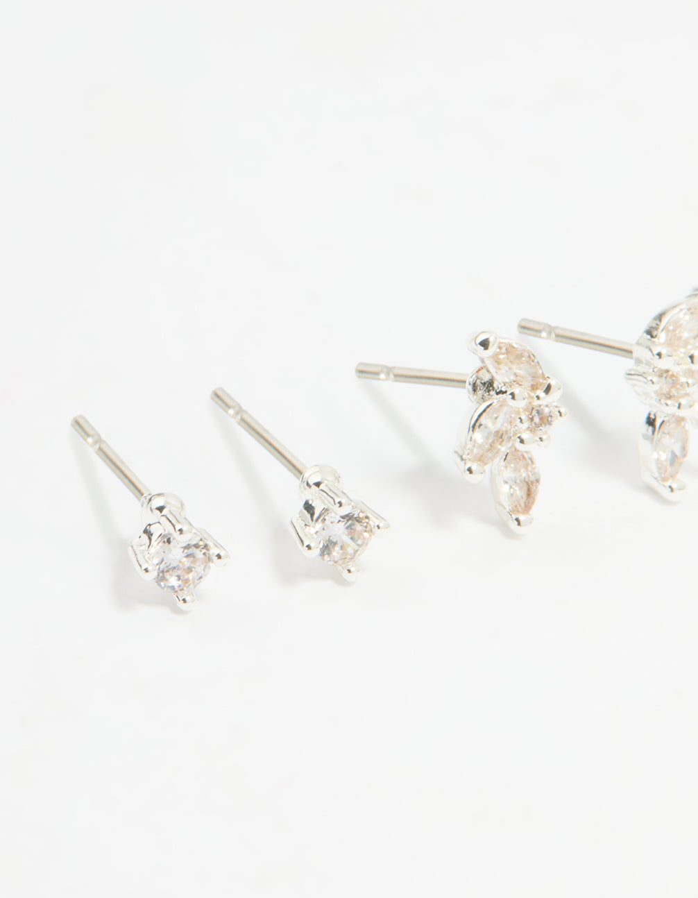 Displaying a flower stud and hoop earrings 4-pack with floral patterns crafted from cubic zirconia, crystal, and silver plated brass featuring stud, huggie closures in silver close up view