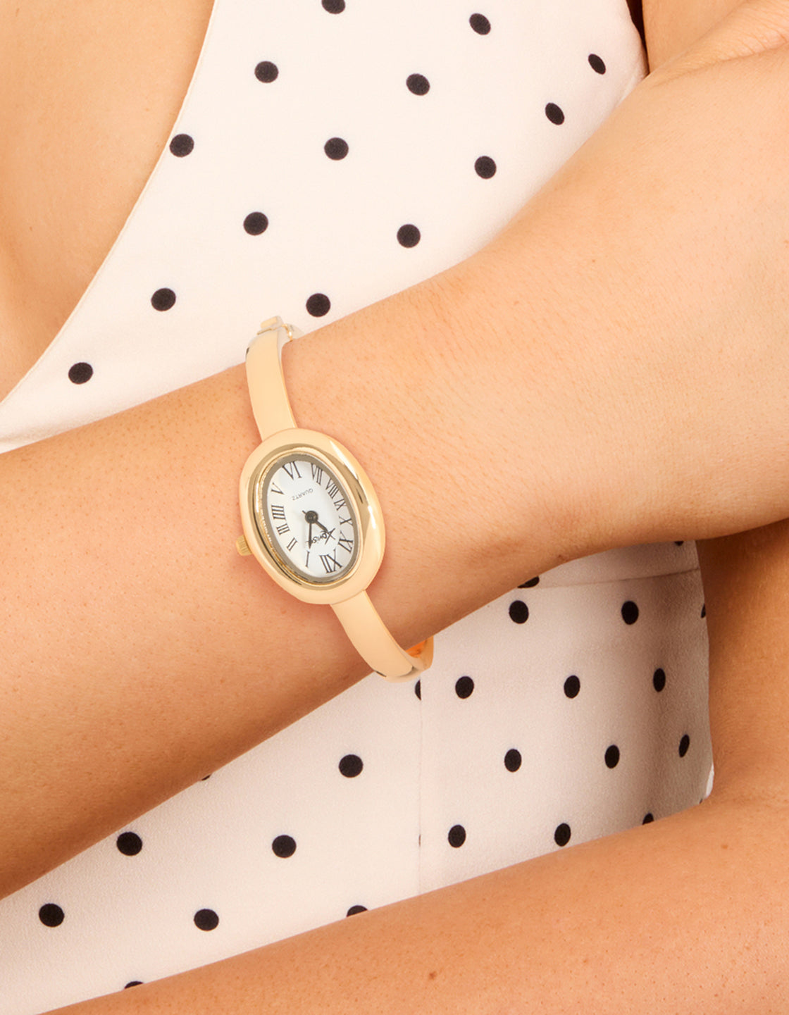 Discover this women's analog oval statement bangle watch featuring a white dial with roman numerals and a gold band design, crafted for casual occasions on wrist view