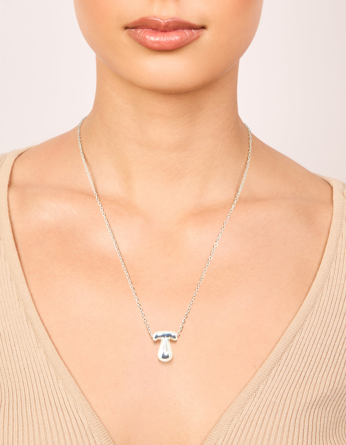 Crafted from waterproof stainless steel, this large bubble letter T necklace with initials pendant in silver on neck view