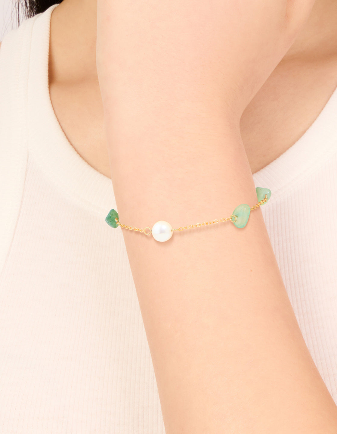 Showcasing a waterproof gold-plated stainless steel bracelet with pearl beads and green semi precious stone chips on wrist view