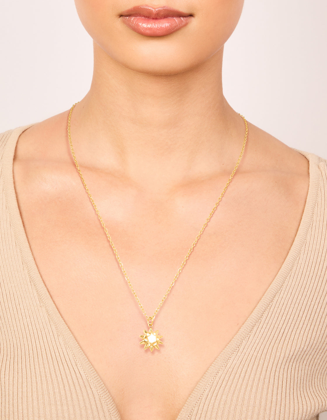 Featuring a waterproof gold plated stainless steel sun pendant necklace with celestial design on neck view