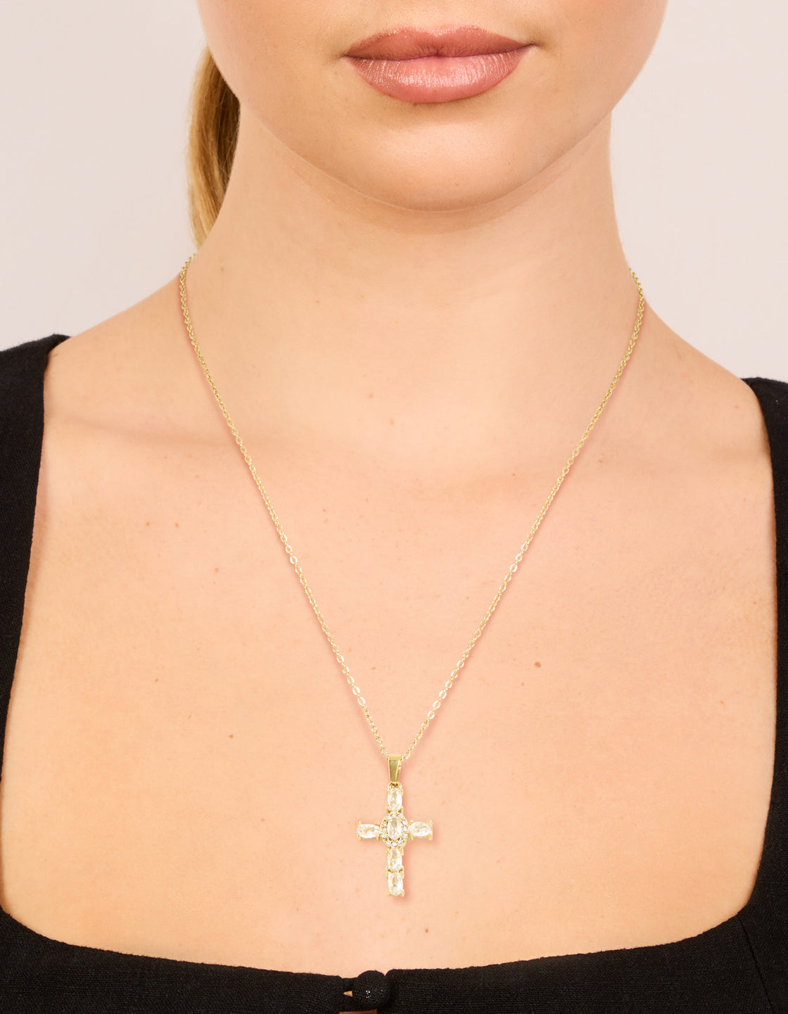 Showcasing a waterproof gold plated stainless steel cubic zirconia dainty cross pendant necklace on neck view
