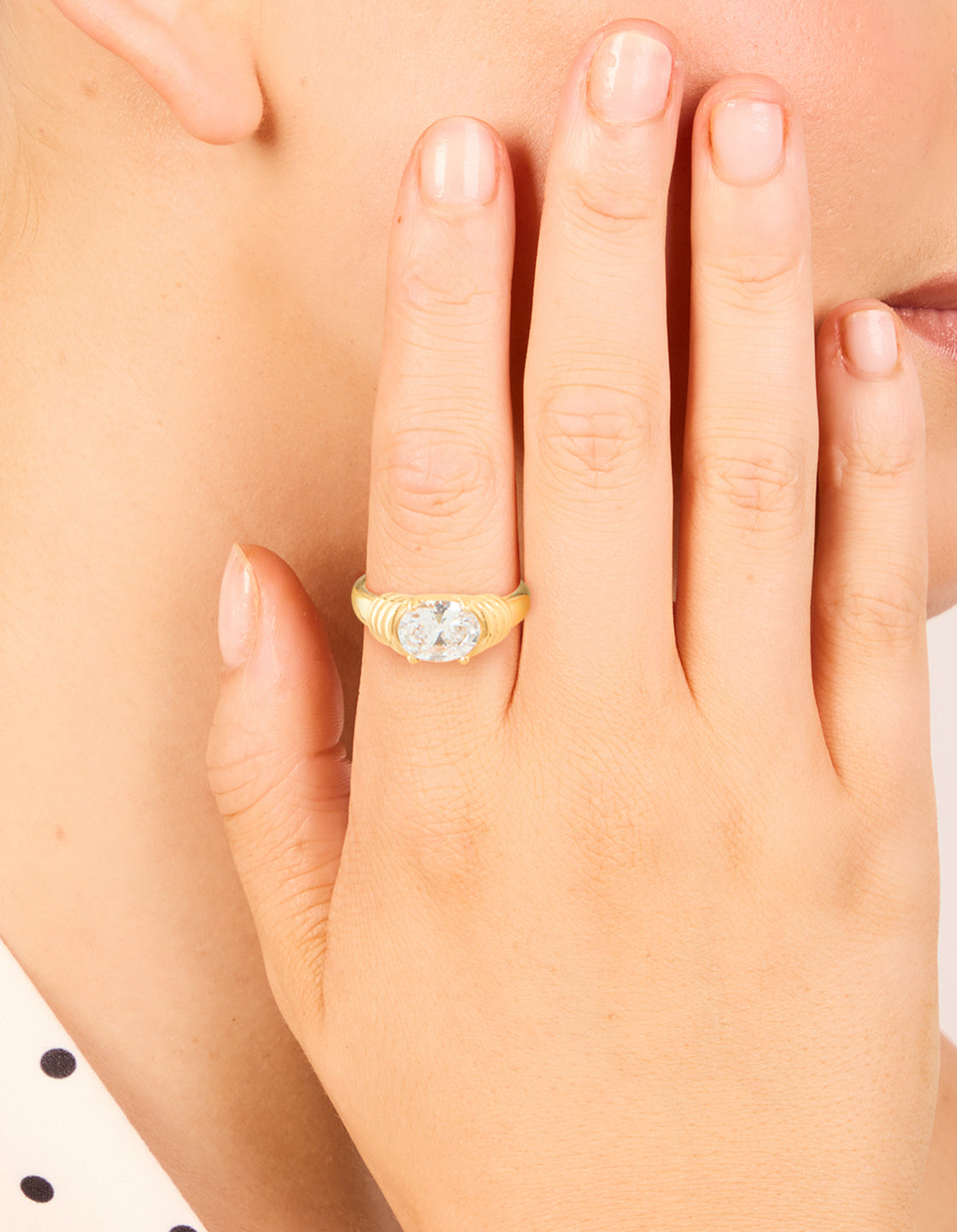 Showcasing a waterproof gold plated stainless steel ring with oval cubic zirconia crystal and ribbed band on finger view