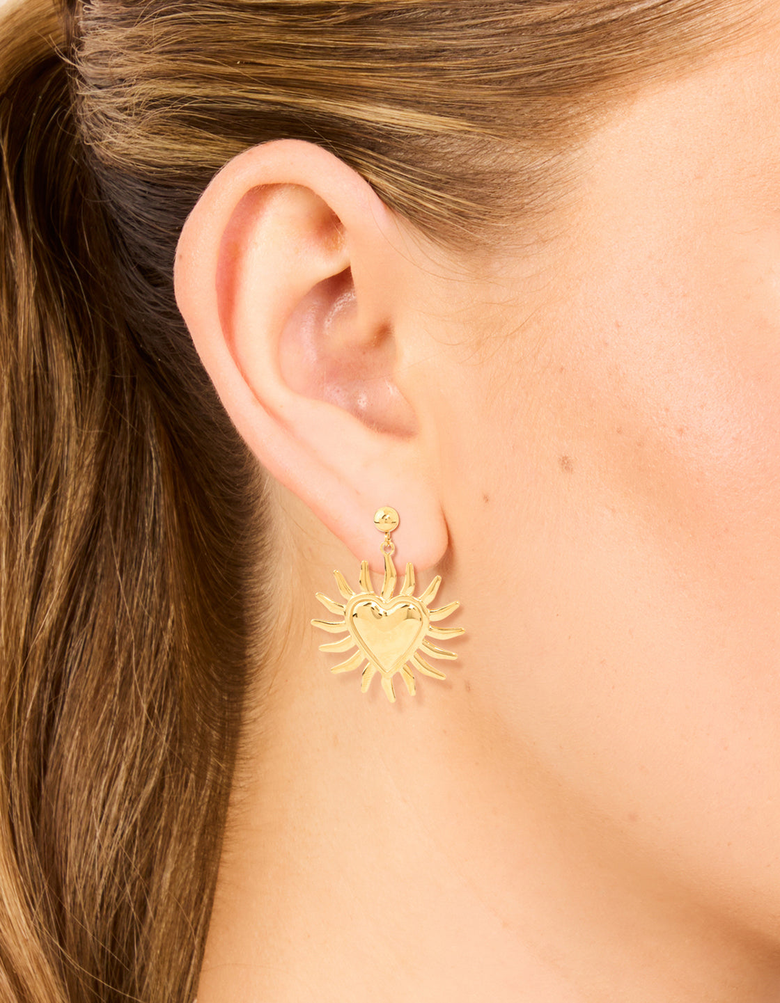 Featuring statement earrings with celestial and heart motifs crafted from waterproof gold plated stainless steel on ear view