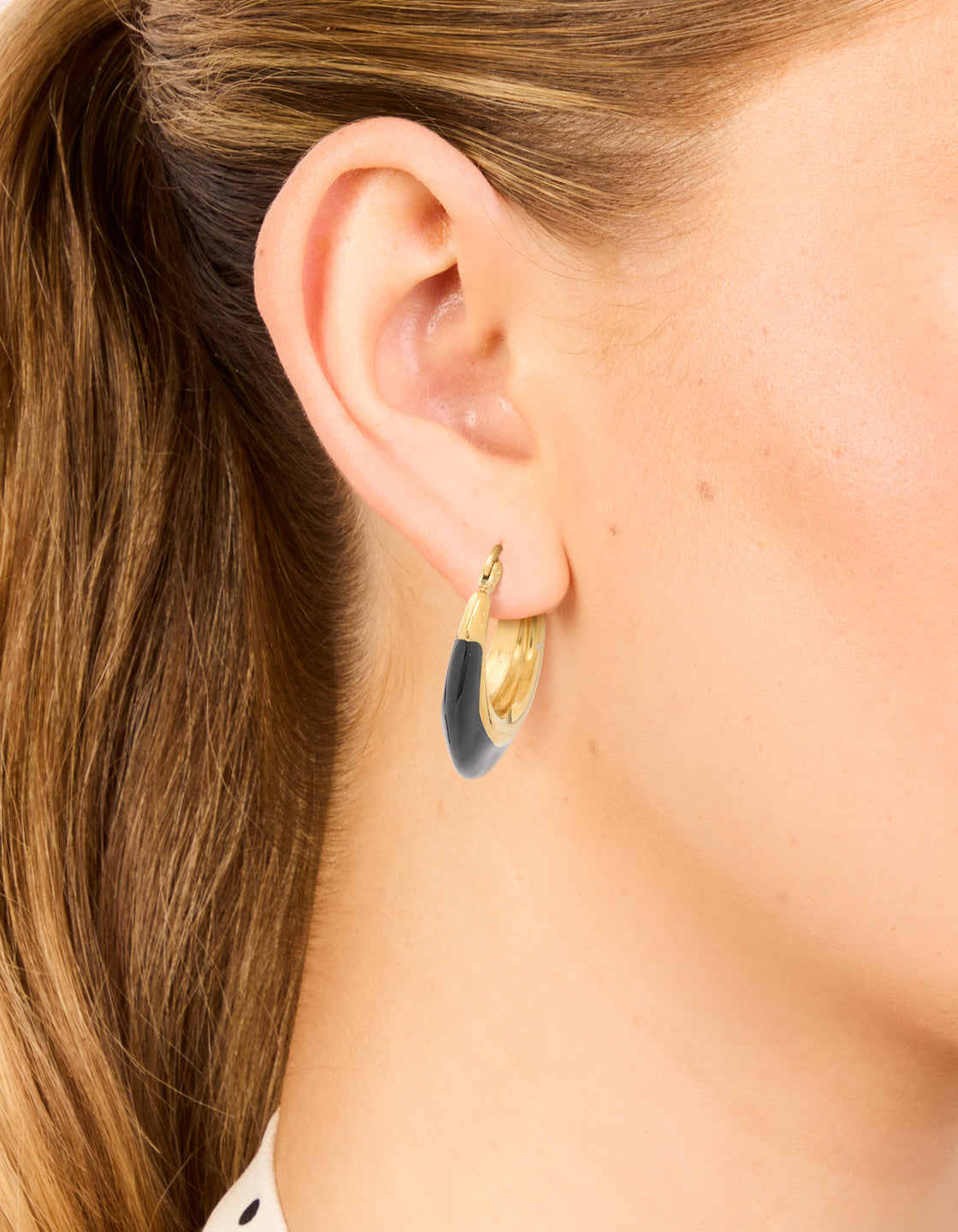 Featuring waterproof gold plated stainless steel short hoop earrings with black enamel on ear view