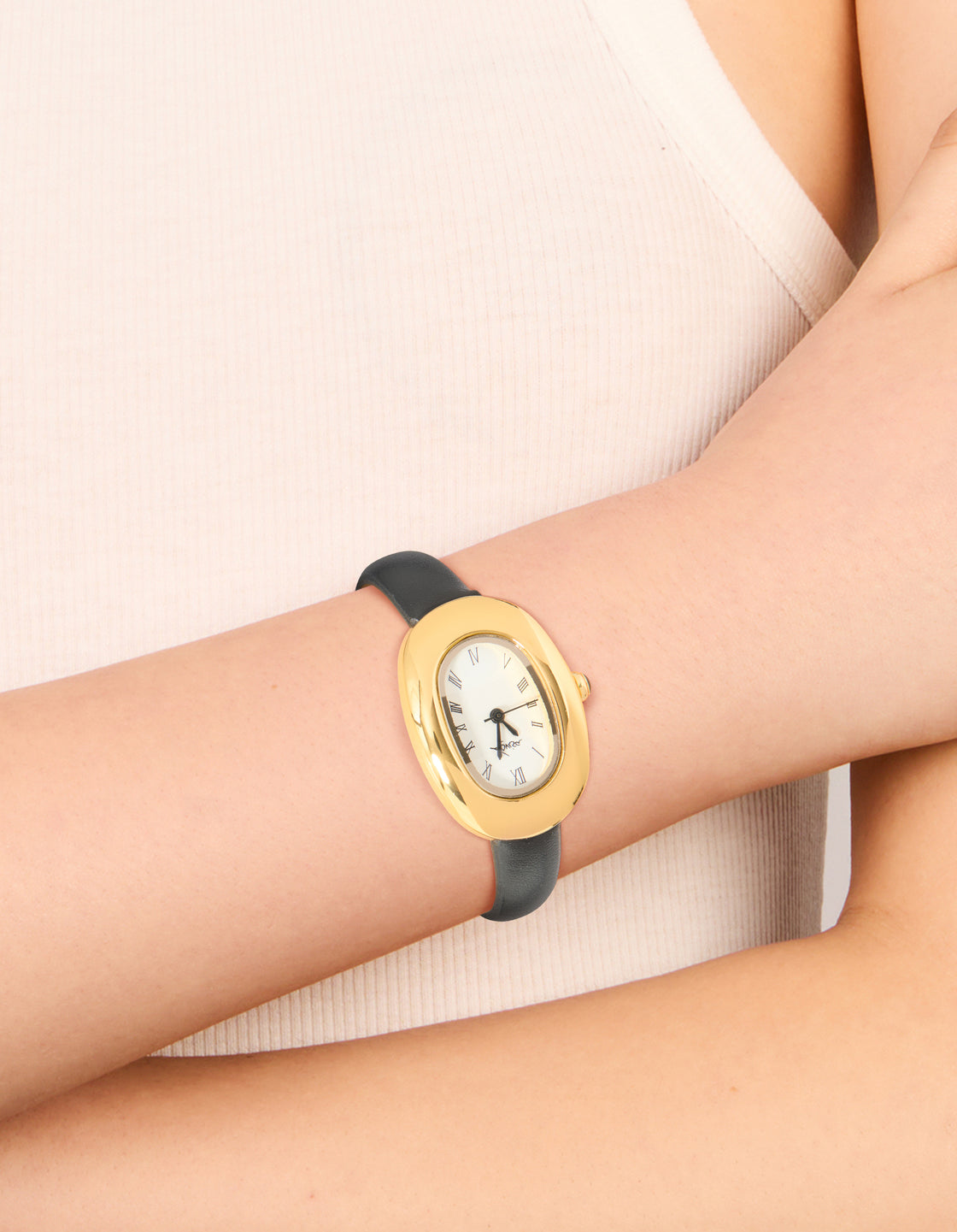 Featuring a women's analog watch with white dial showcasing roman numerals in a oval case, designed with casual styling, crafted from PU leather strap in black on wrist view