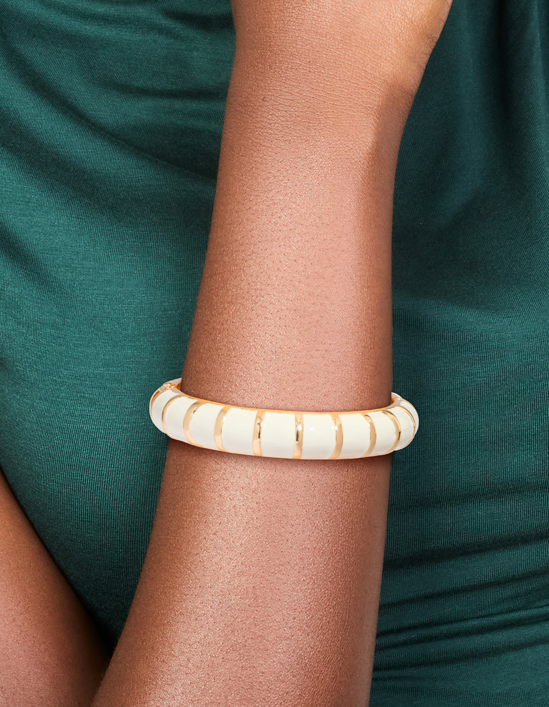 Showcasing a striped enamel bangle in gold and ivory, designed as a comfortable accessory on wrist view