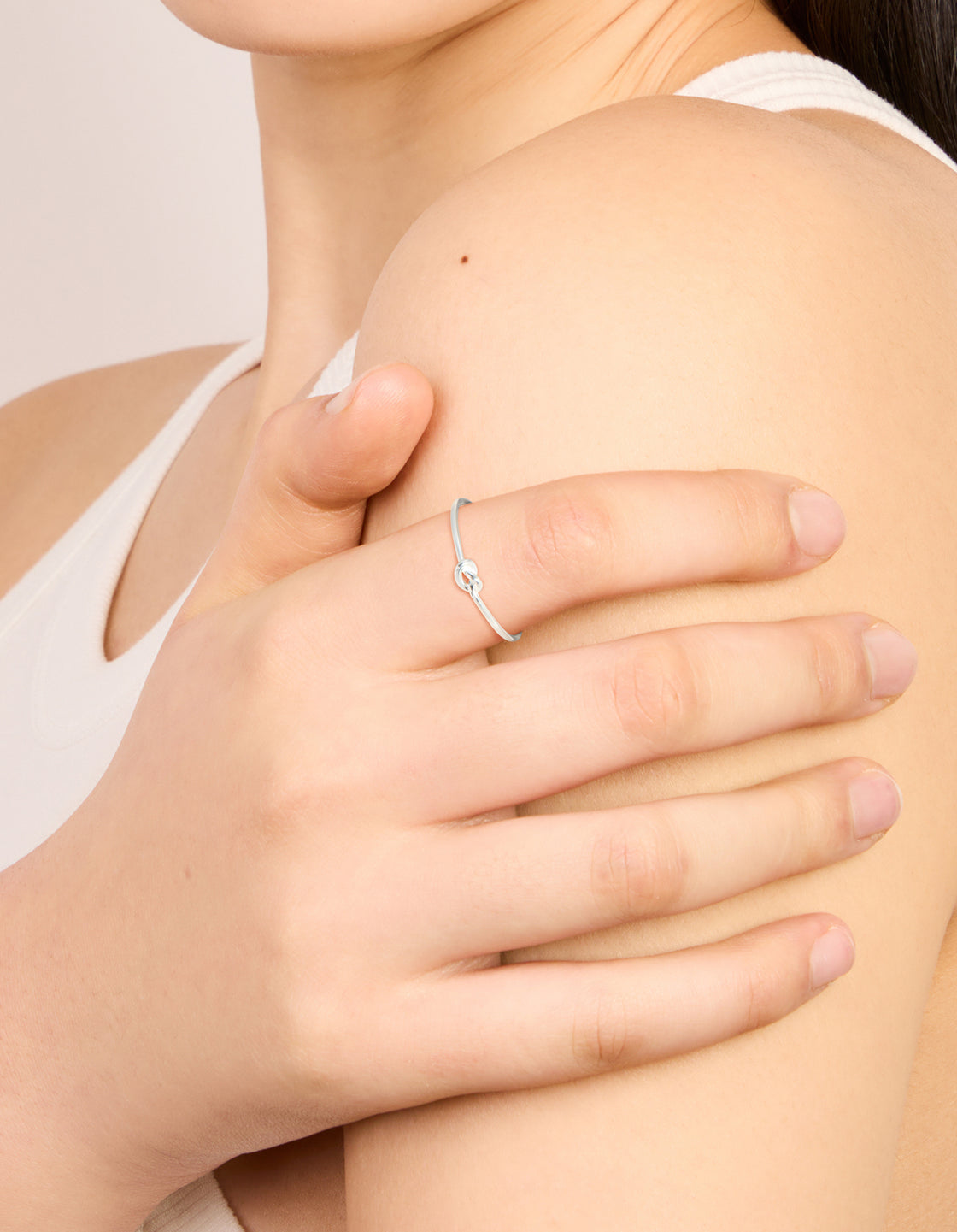 Delicate sterling silver tiny knot ring in dainty style on finger view