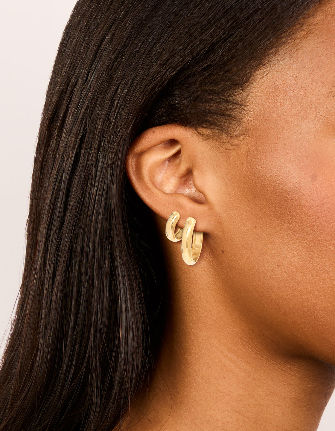 Featuring waterproof gold plated stainless steel thick, small and large hoop earrings in a 2-pack with chunky statement styling on ear view