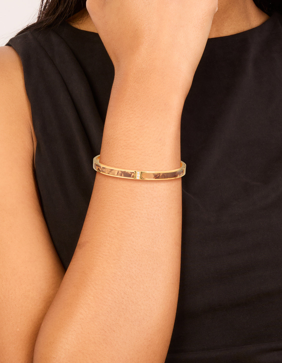 Showcasing a waterproof gold plated stainless steel hinged bangle with brown pearlised inlay on wrist view