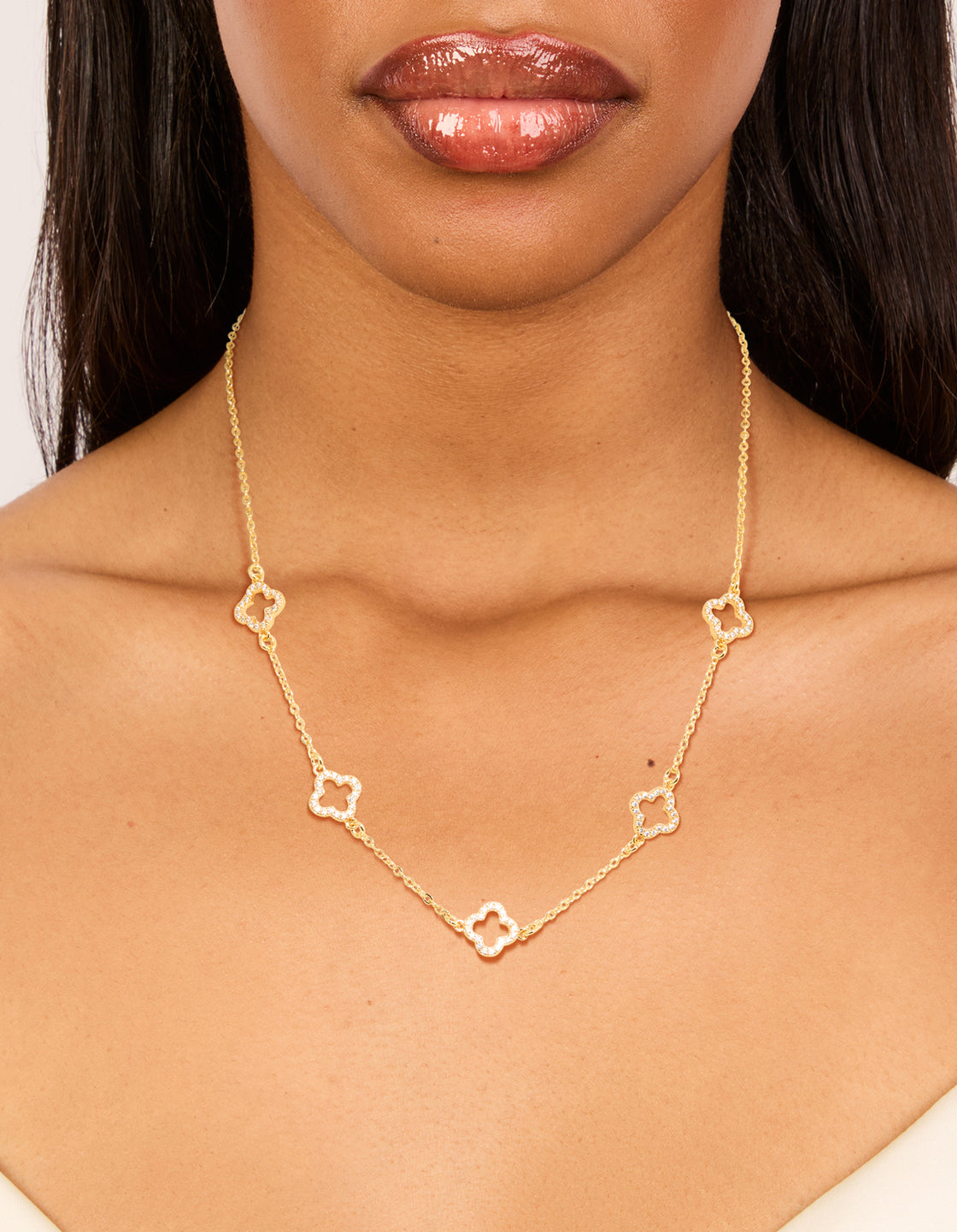 Showcasing a gold plated necklace with cubic zirconia flower charm on neck view