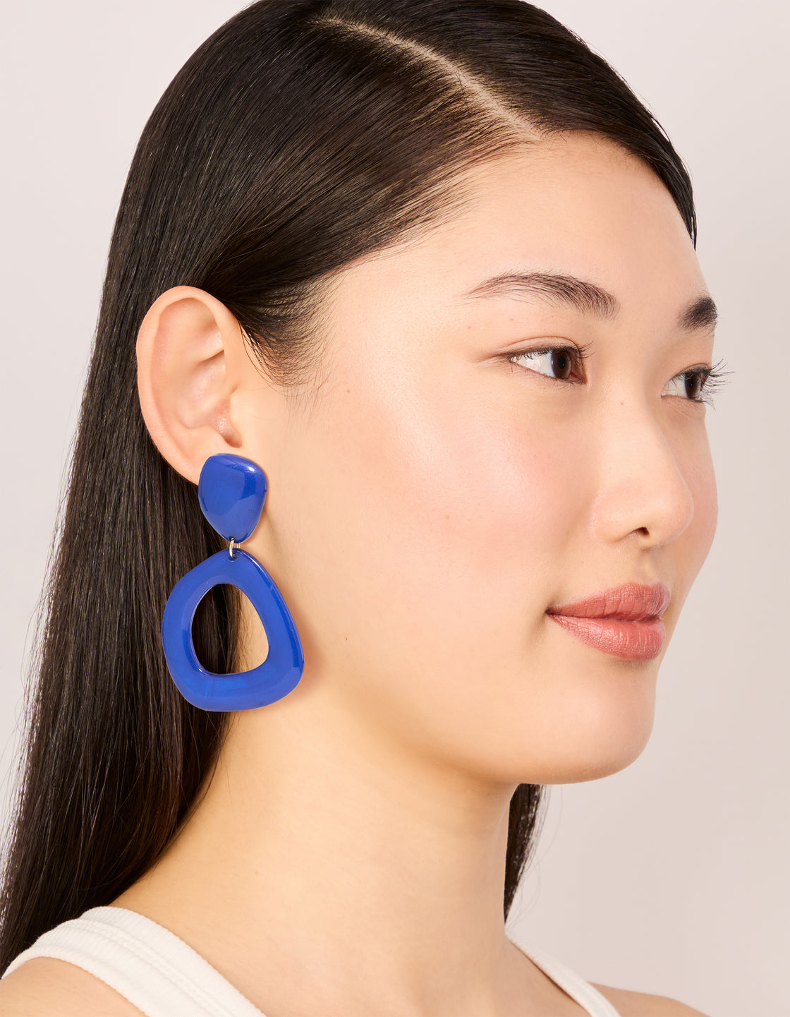 Displaying dark blue acrylic organic square-oval drop earrings in statement style with on model view