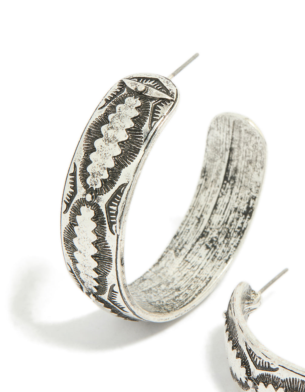 Showcasing antique silver textured hoop earrings featuring ornate engraved patterns in close up view