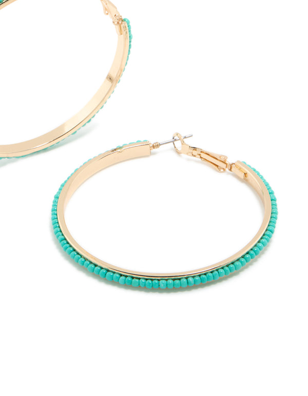 Designed with large thin aqua beaded hoop earrings in turquoise and gold post detail view