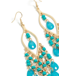 Elegant gold blue beaded oval fish hook drop earrings with charm and turquoise accents close up view - link has visual effect only