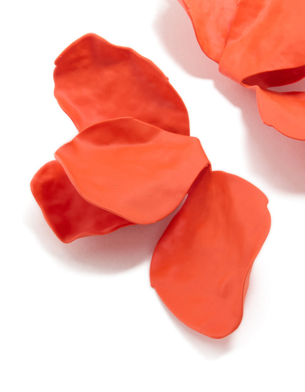 Highlighting orange coated metal flower petal drop earrings with floral design in close up view