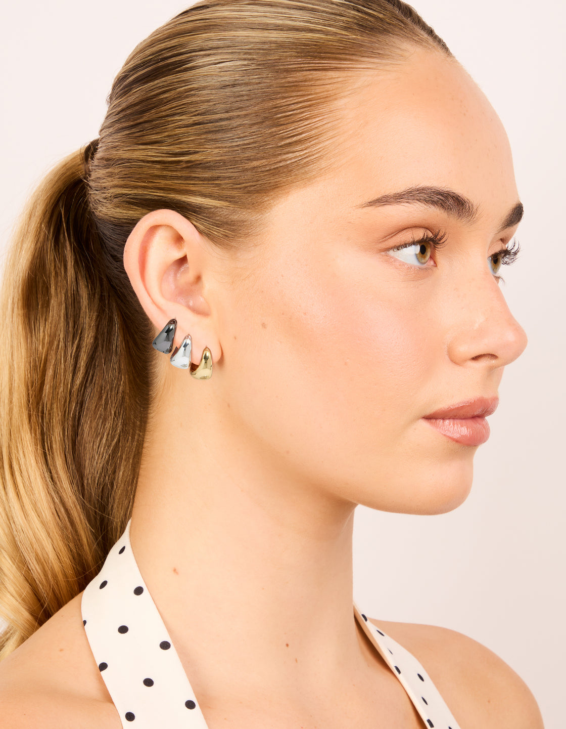 Crafted with mixed metal small graduated huggie earrings in a 3-pack with silver plated and gold plated finishes on model view