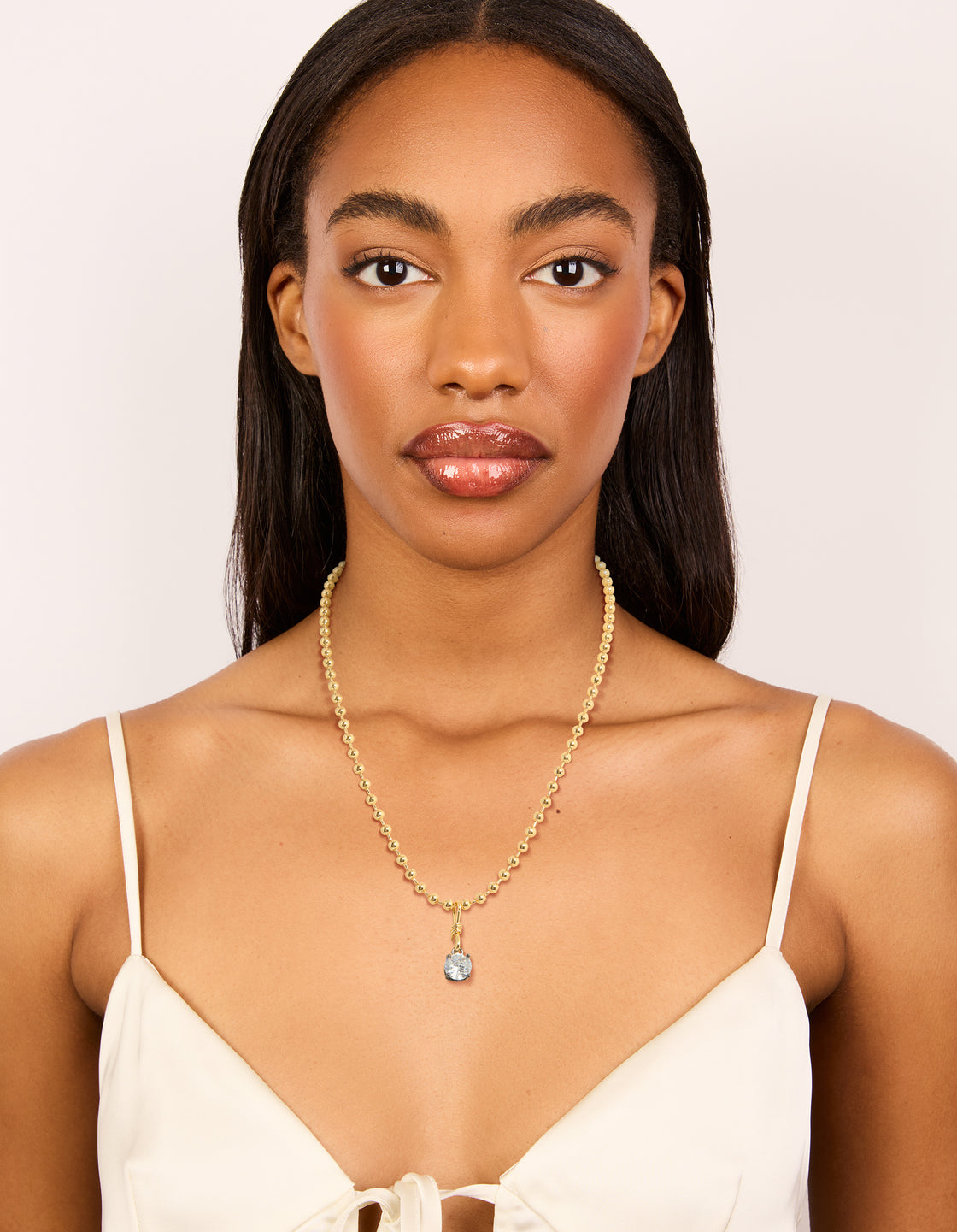 Displaying a mixed metal plated cubic zirconia pendant and ball chain necklace with crystal in gold on model view