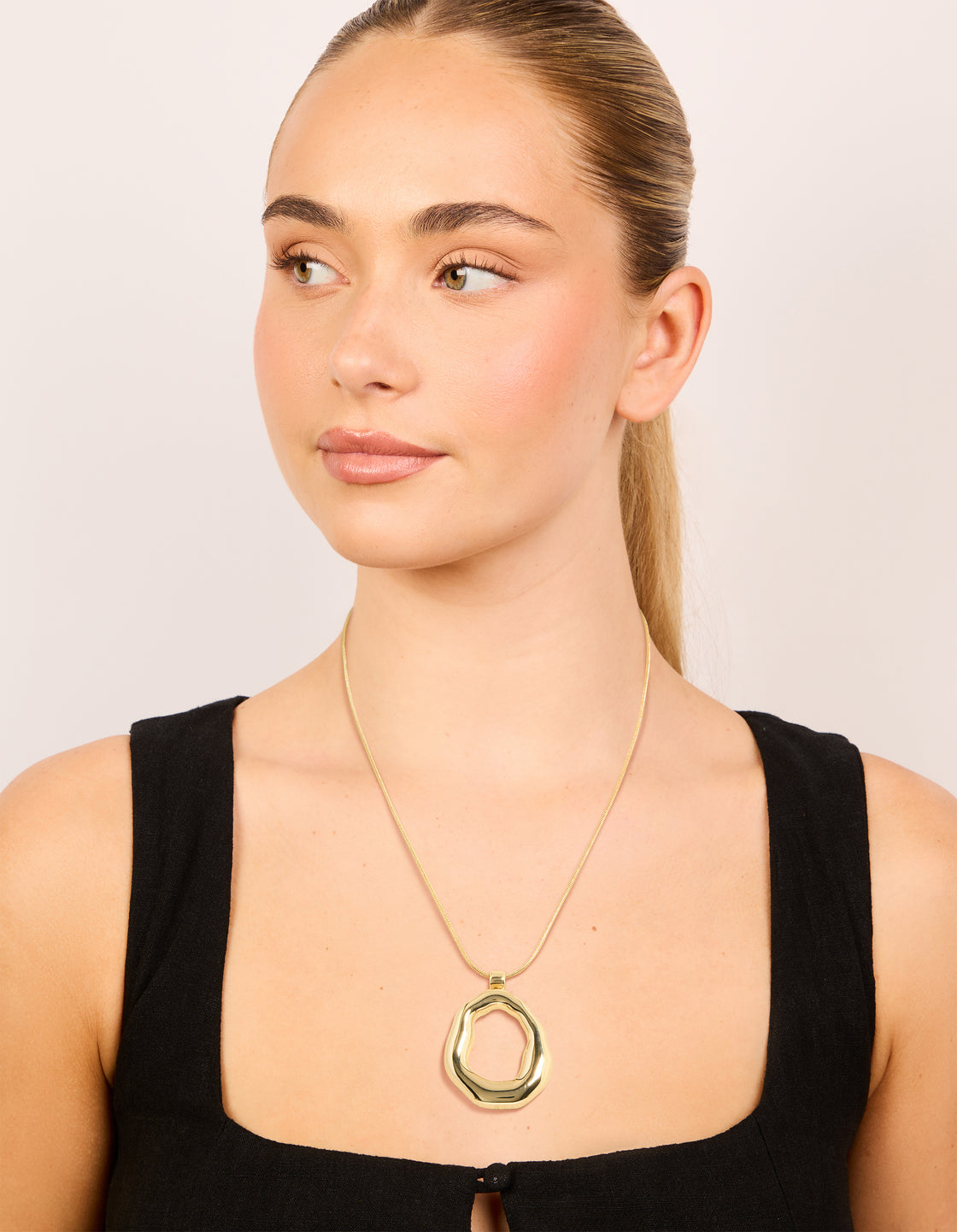 Designed with a gold plated organic circle pendant necklace on model view
