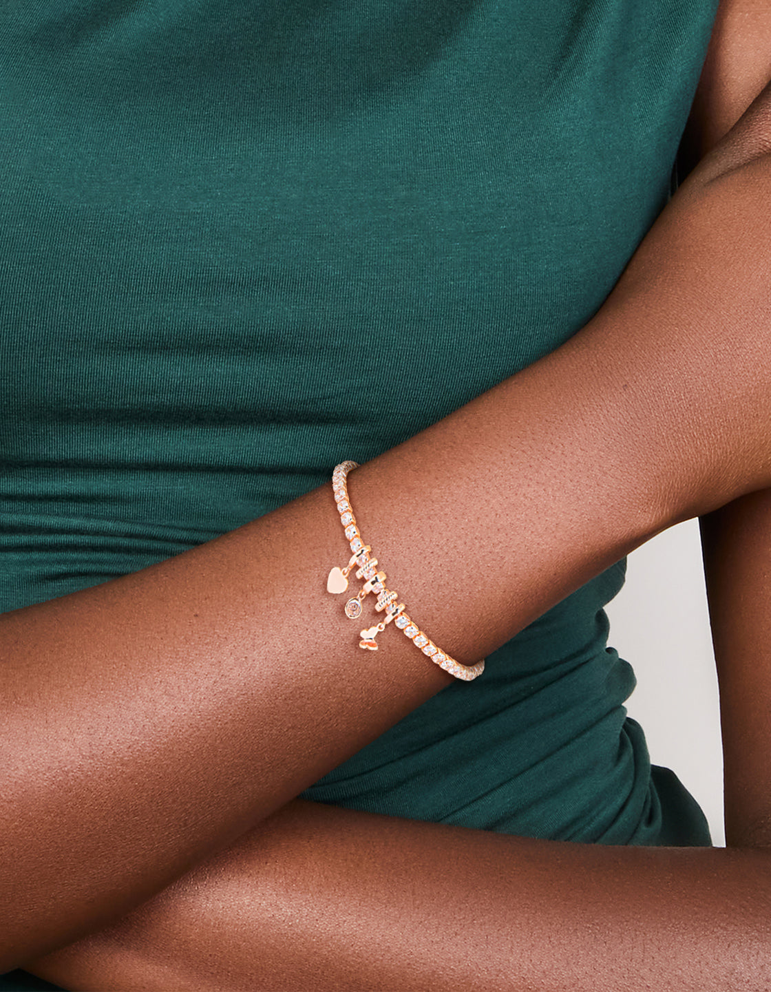 Elegant tennis bracelet featuring butterfly and heart charms in rose gold plated cubic zirconia on wrist view