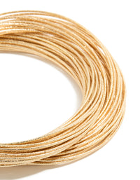 This multi crossover bangle features worn gold finish in close up view - link has visual effect only